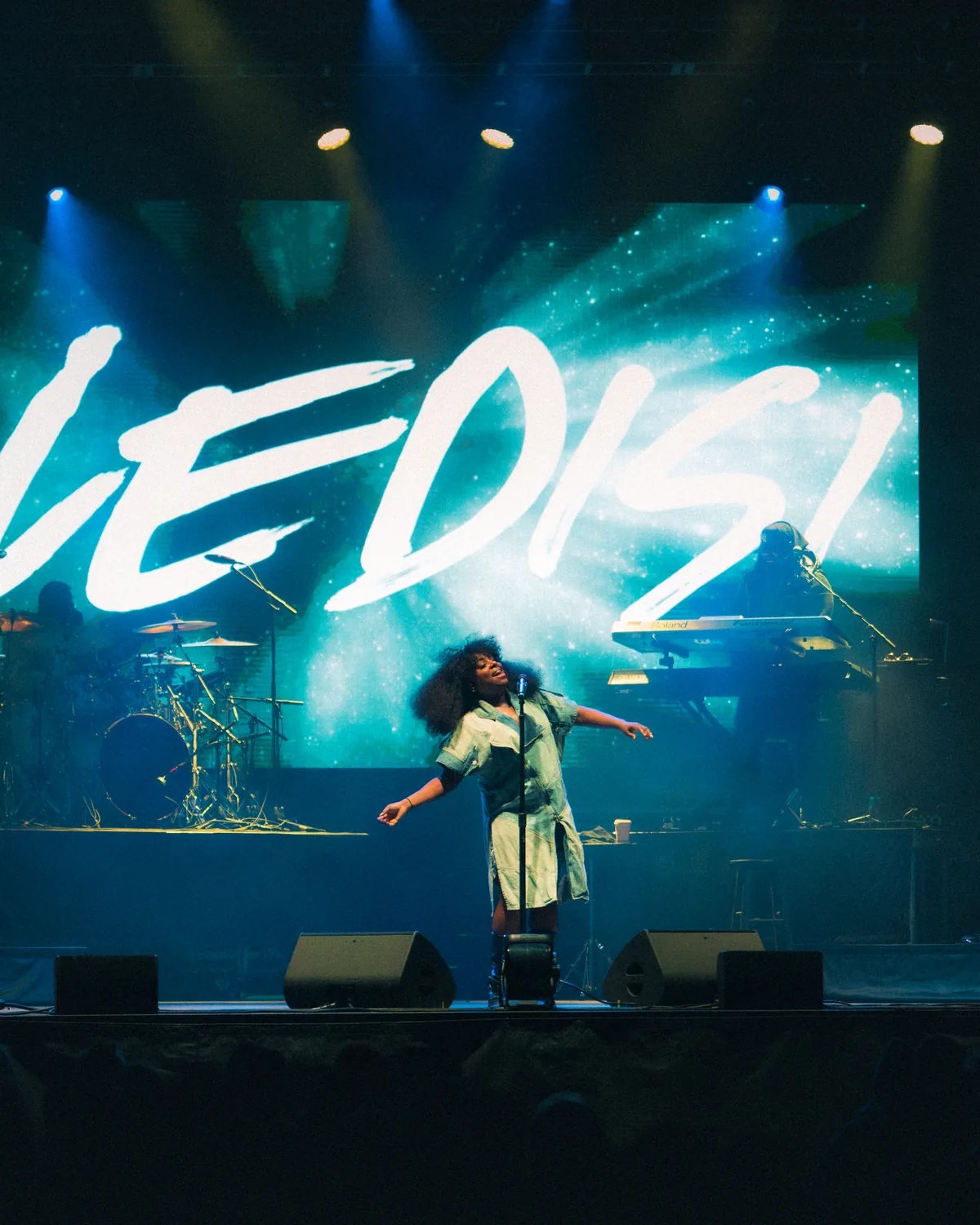 Ledisi performing energetically on stage with arms outstretched