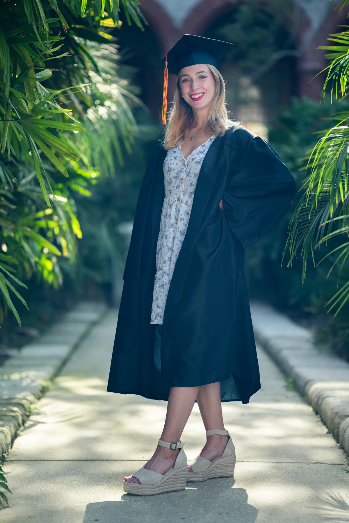 Flagler College graduate walking through lush garden pathway on campus