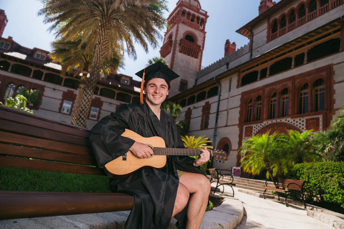 Flagler College graduate with guitar showing personal interests during grad photo session