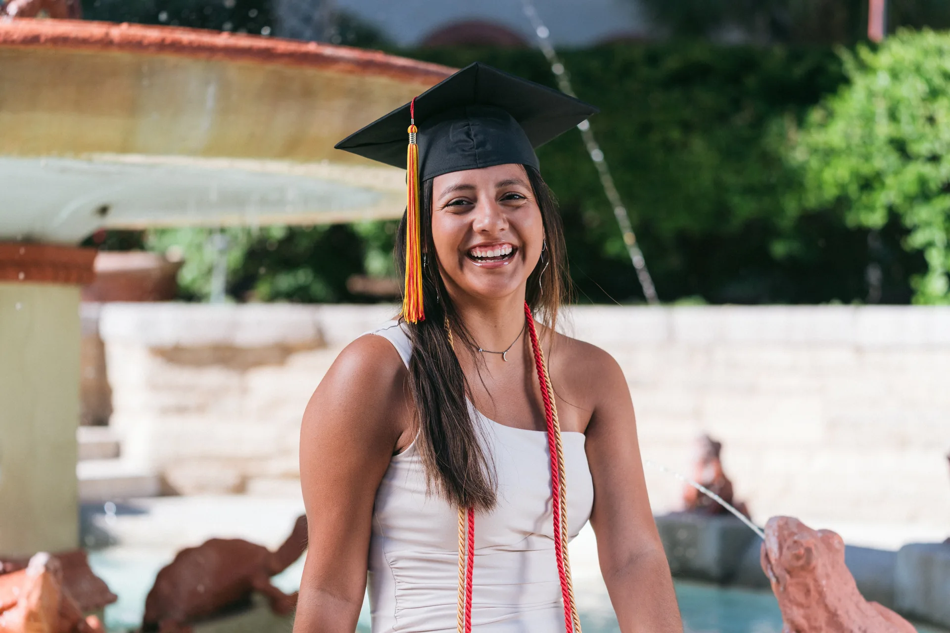 Joyful Flagler College graduate laughing by the fountain at Ponce Hall