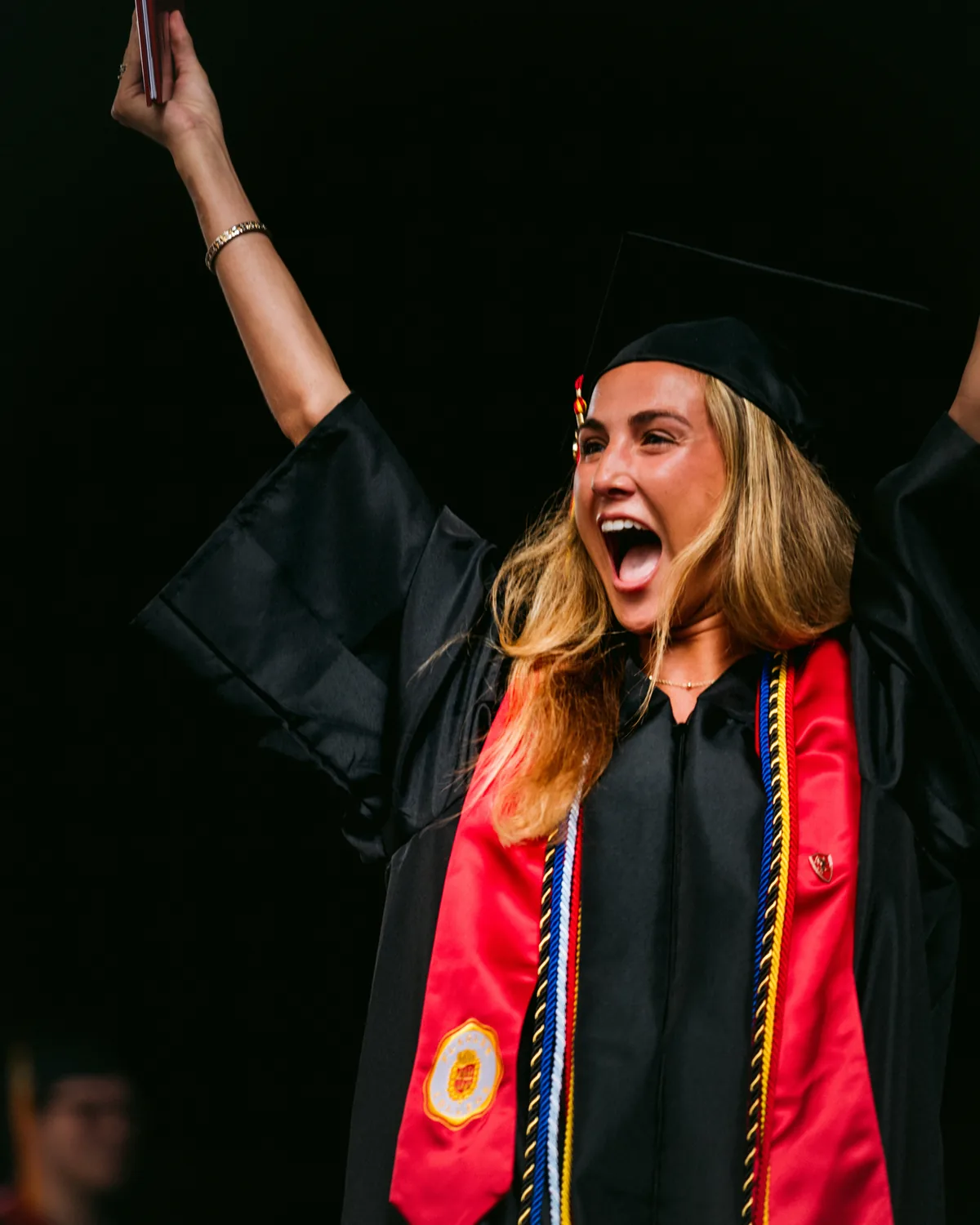 Flagler College graduate celebrating at commencement with arms raised — First Sight Films