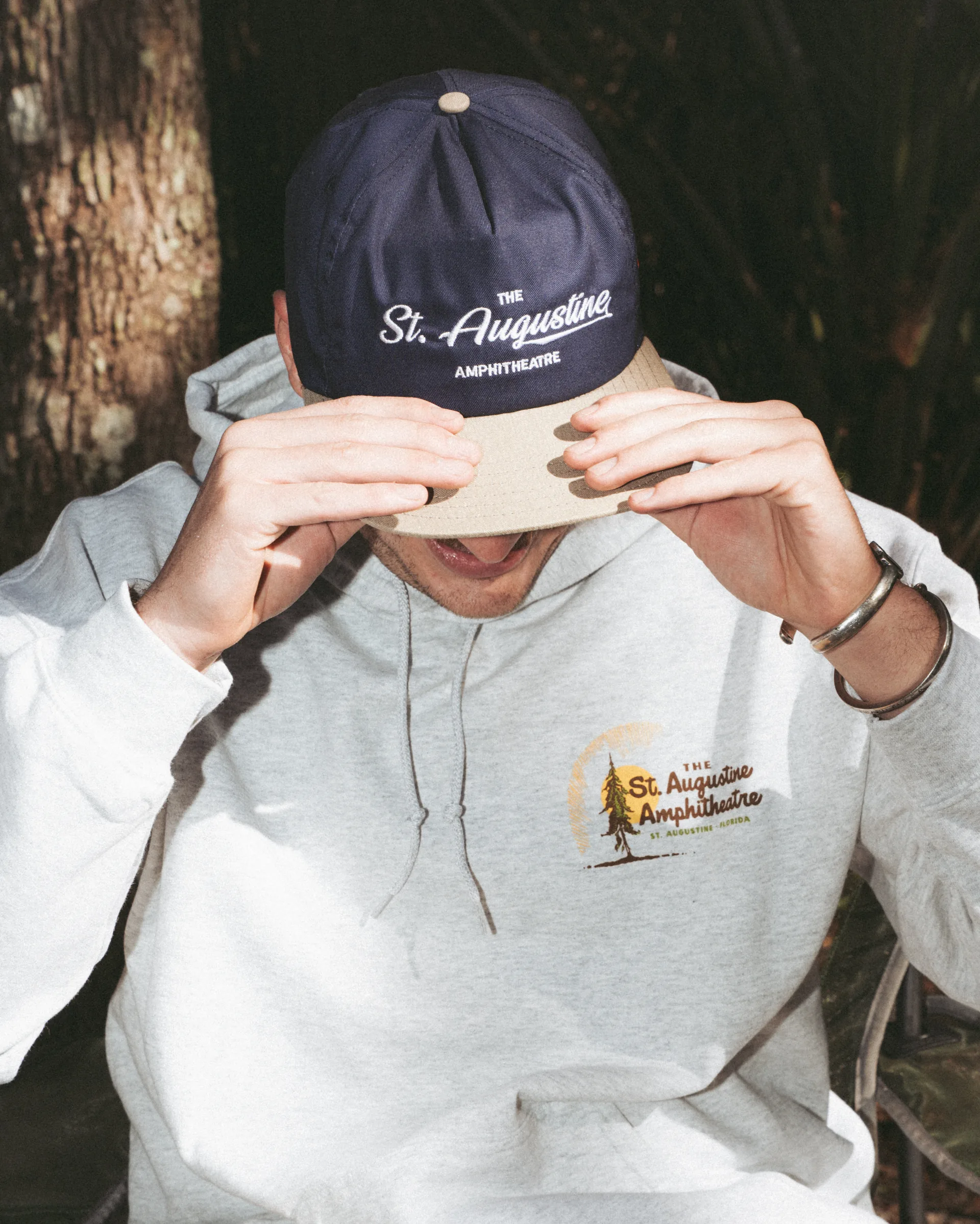 Model wearing a St. Augustine Amphitheatre cap and logo hoodie